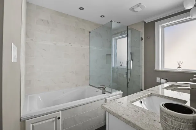 a bathroom with a granite countertop sink mirror vanity and a bathtub