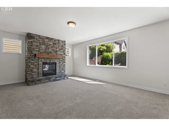 an empty room with windows and fireplace