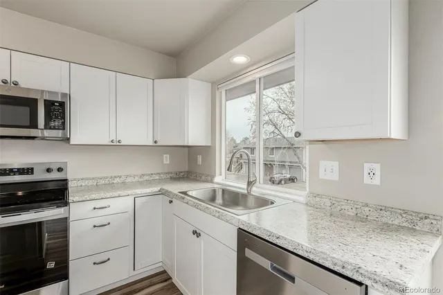 a kitchen with stainless steel appliances granite countertop a sink a stove and cabinets