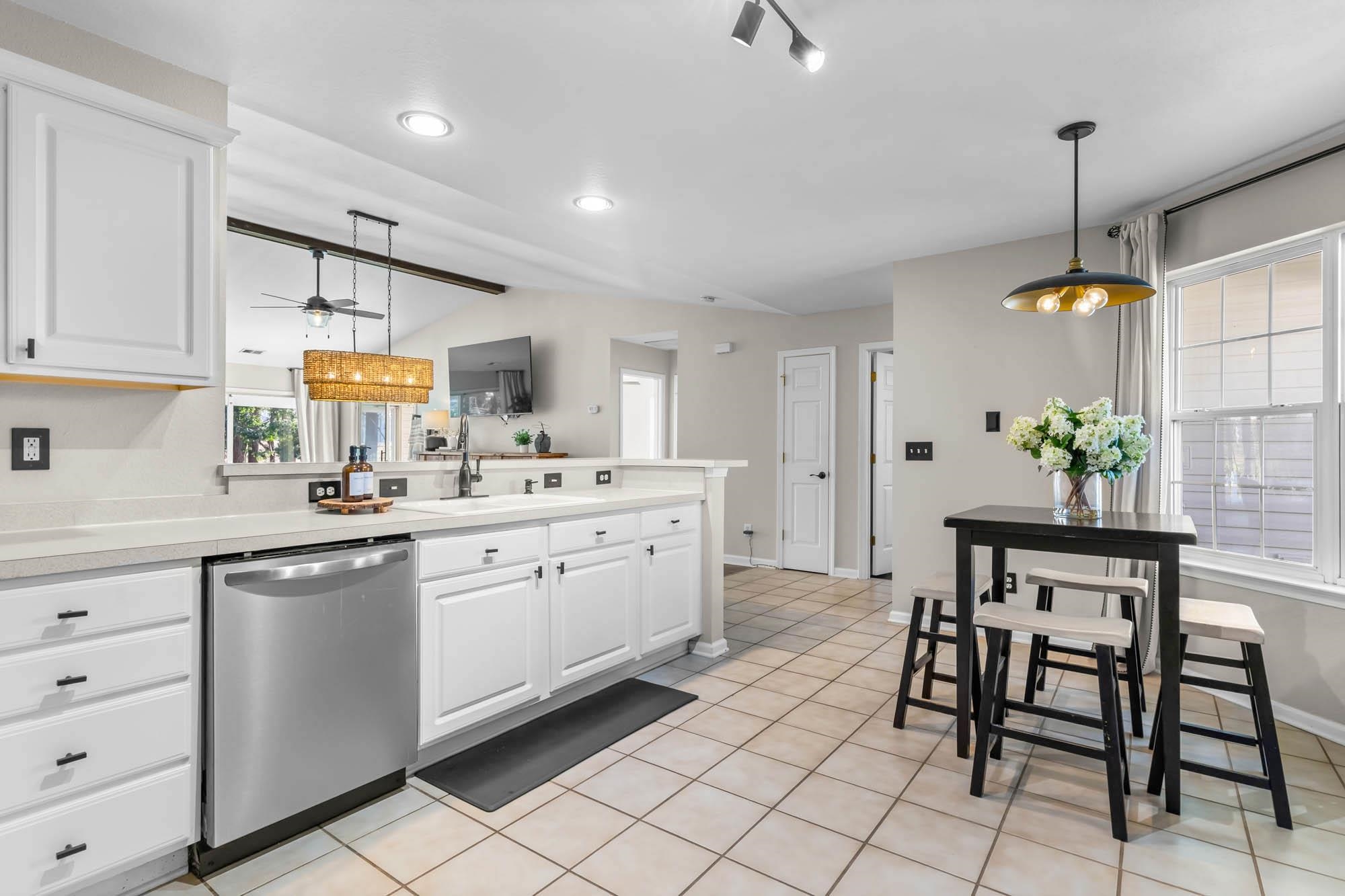 248 McKendree Lane Myrtle Beach, SC 29579 - Photo 5 of 34 Kitchen with white cabinetry, light countertops, stainless steel dishwasher, vaulted ceiling, and light tile patterned floors