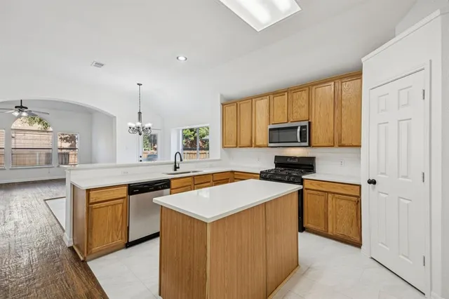 a kitchen with stainless steel appliances granite countertop a stove top oven a sink dishwasher and a refrigerator with wooden floor