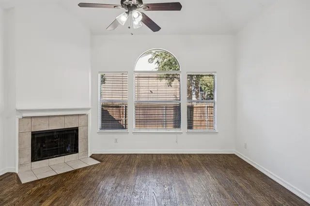an empty room with wooden floor a fireplace and a window