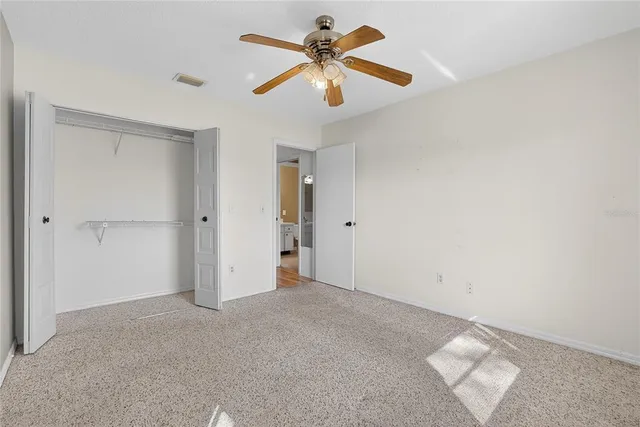 an empty room with closet and a chandelier fan