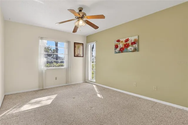 an empty room with windows and fan