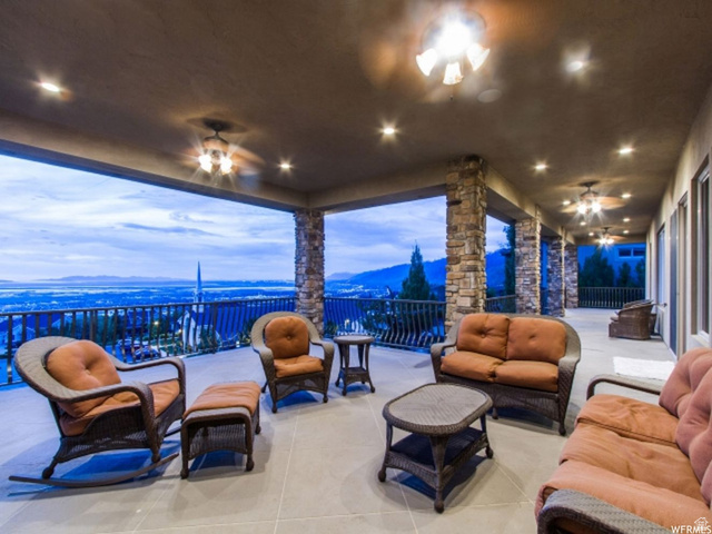 4378 Foothill Drive Bountiful, UT 84010 - Photo 41 of 46 Expansive covered patio featuring multiple ceiling fans with integrated lighting, recessed ceiling lights, stone-clad support columns, and a railing overlooking a distant landscape