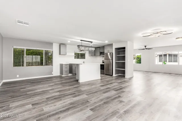 an empty room with wooden floor and a kitchen