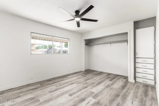 a view of empty room with wooden floor and fan