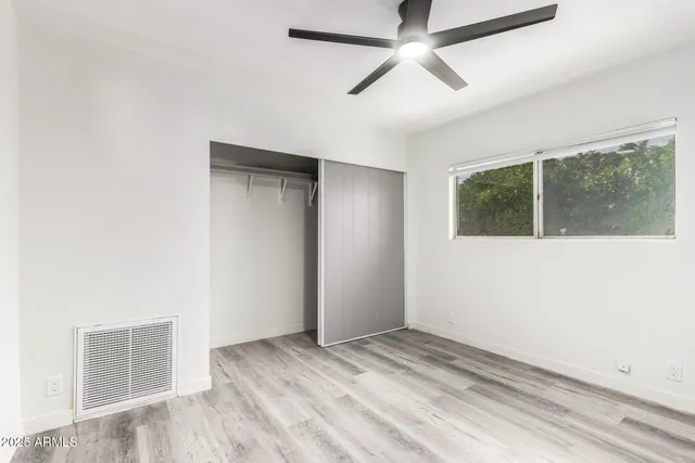 a view of empty room with wooden floor and fan