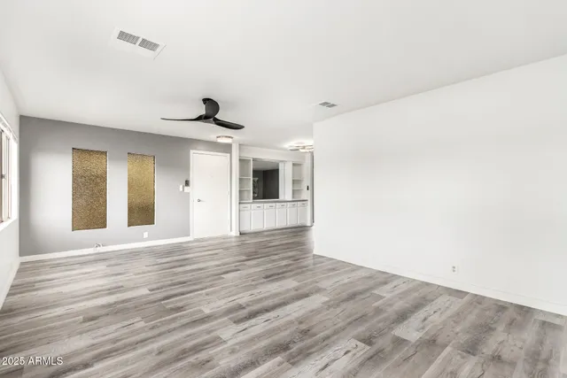 a view of an empty room with wooden floor and a window