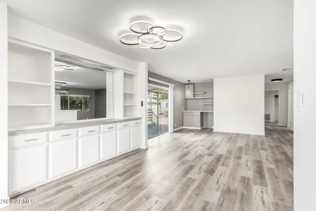 a large white kitchen with granite countertop cabinets a sink dishwasher and a stove with wooden floor