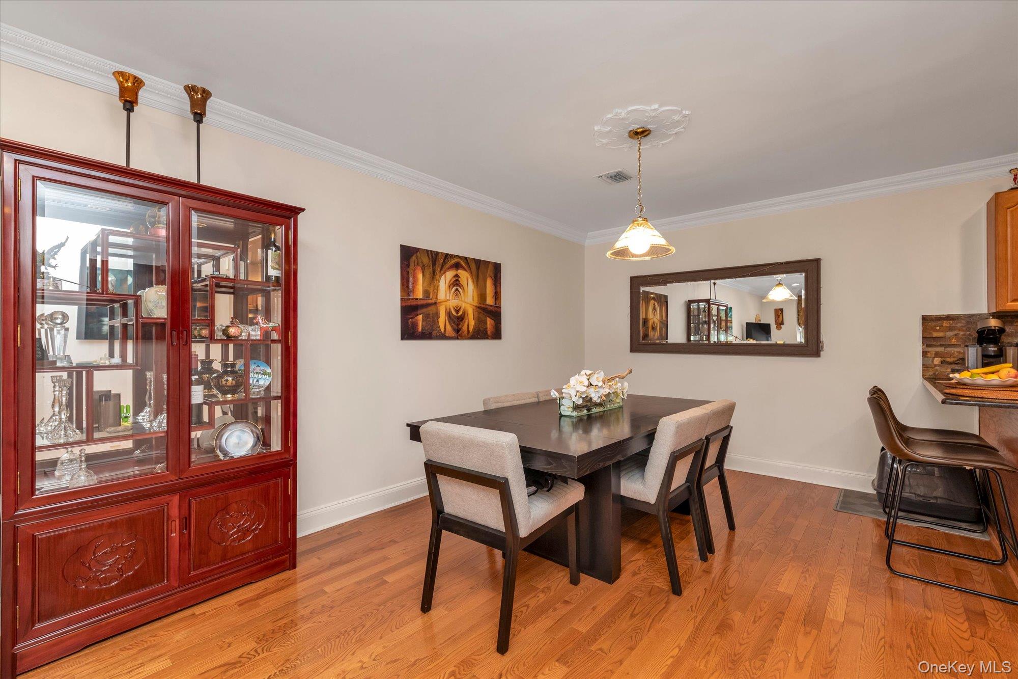 150 I U Willets Road Albertson, NY 11507 - Photo 6 of 21 Dining room featuring wood-finish flooring, crown molding, and a decorative ceiling medallion with a pendant light fixture
