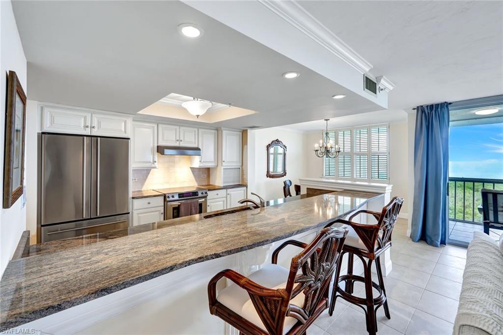 6573 Marissa Loop, Unit 2003 Naples, FL 34108 - Photo 11 of 41 a dining hall with stainless steel appliances granite countertop a stove a refrigerator a sink a dining table and chairs with wooden floor
