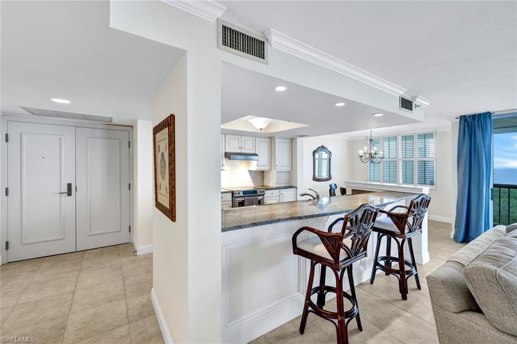 6573 Marissa Loop, Unit 2003 Naples, FL 34108 - Photo 9 of 41 a view of a dining room and livingroom with furniture a rug a fireplace and wooden floor