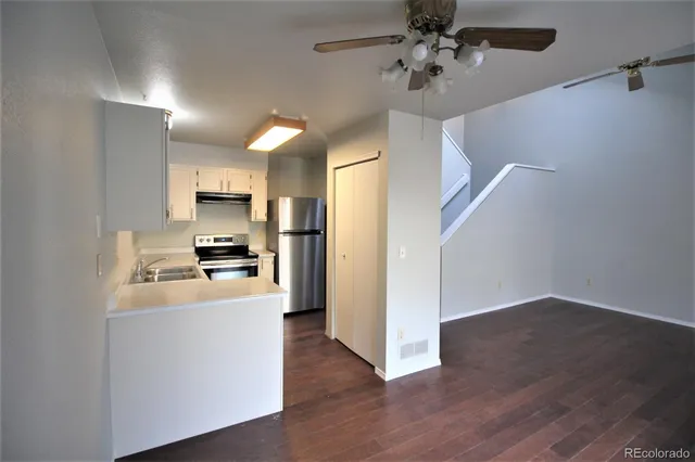 a view of a kitchen with a sink a refrigerator a ceiling fan and wooden floor