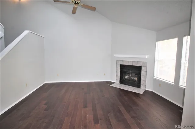 an empty room with wooden floor fireplace and windows