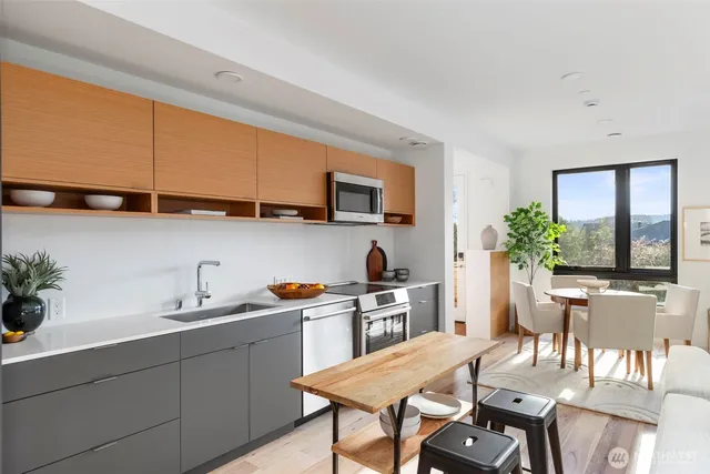 a kitchen with stainless steel appliances granite countertop a sink a stove a dining table and chairs