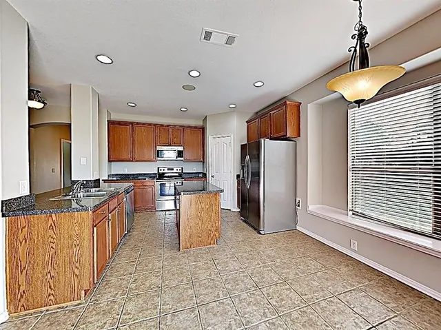 a kitchen with stainless steel appliances granite countertop a refrigerator a stove a sink and a refrigerator