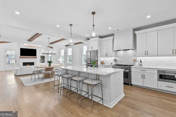 a kitchen with stainless steel appliances a refrigerator a sink a stove a dining table and chairs