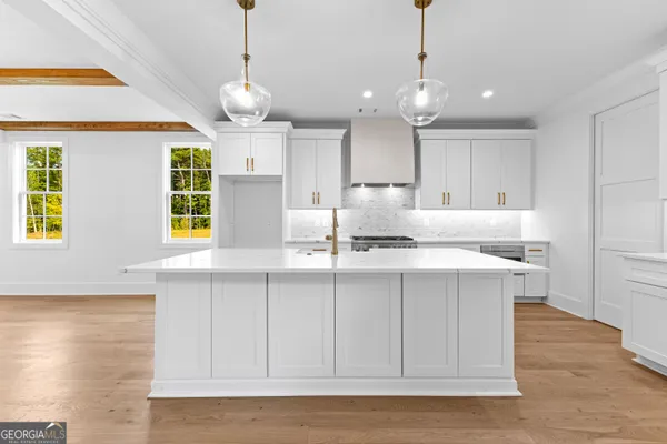 a kitchen with stove a refrigerator and white cabinets with wooden floor