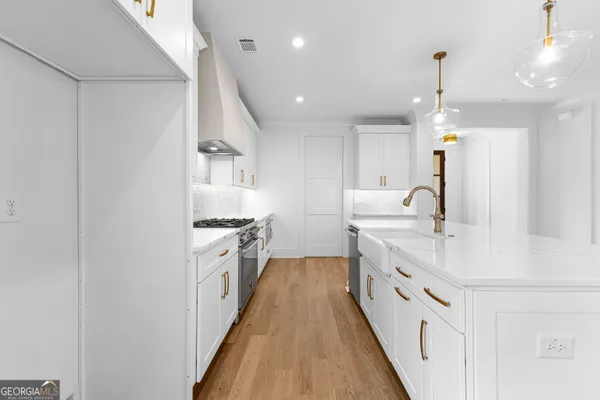 a large white kitchen with a large kitchen island white cabinets and stainless steel appliances