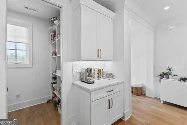a hallway with white cabinets and wooden floor