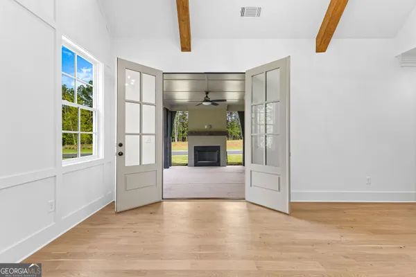 a view of an empty room with a window and wooden floor
