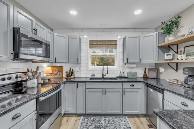 a kitchen with stainless steel appliances granite countertop a sink stove and cabinets