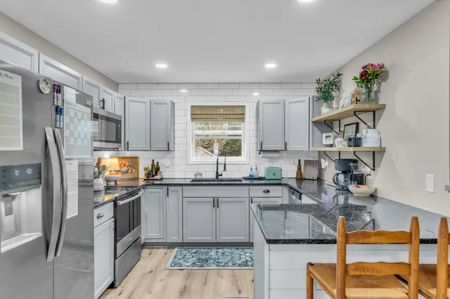 a kitchen with granite countertop a sink stove and refrigerator