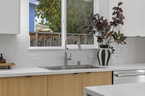 a view of a sink a mirror and window in a kitchen