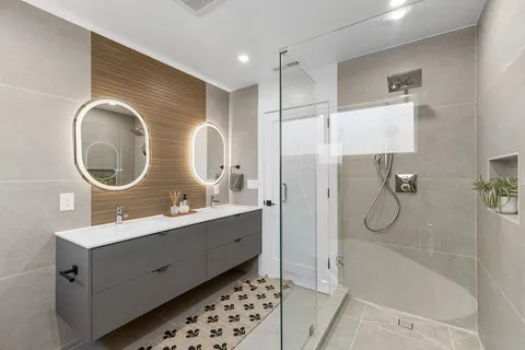 a bathroom with a double vanity sink mirror and shower