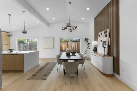 a dining room with stainless steel appliances kitchen island granite countertop a table chairs and a refrigerator