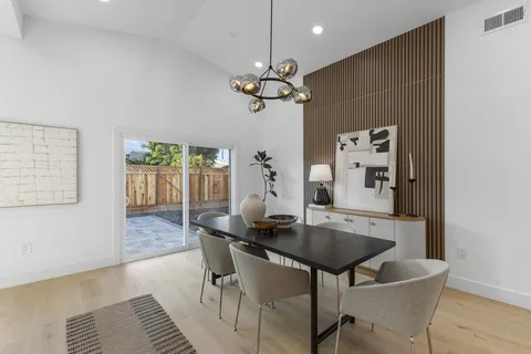 a dining room with wooden floor a chandelier a wooden table and chairs