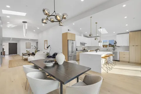 a open dining room with stainless steel appliances kitchen island granite countertop a table chairs and a refrigerator