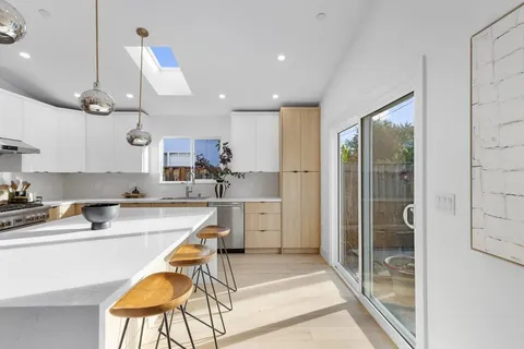 a kitchen with stainless steel appliances granite countertop a refrigerator a sink a stove and white cabinets with wooden floor