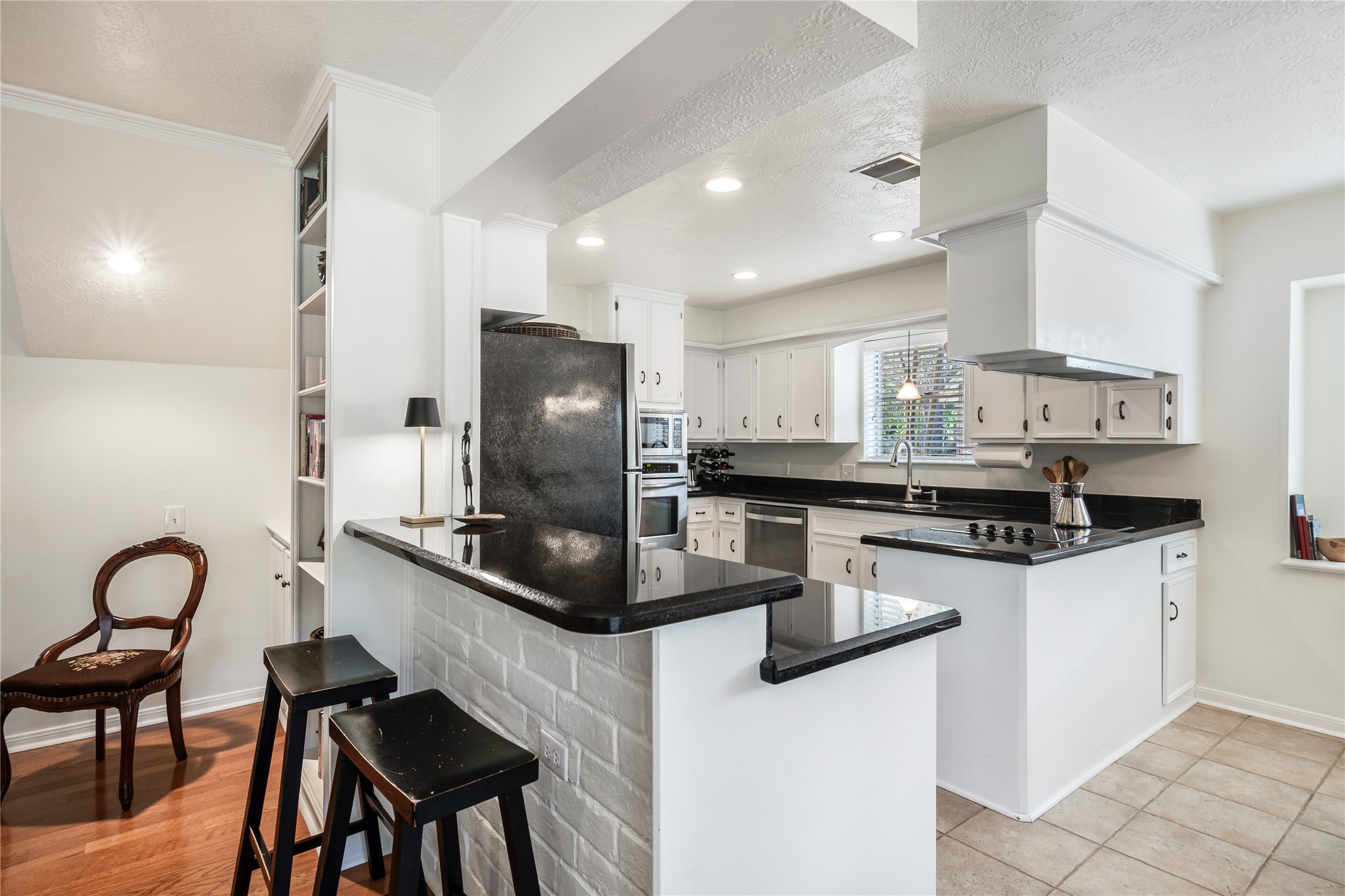 7622 Feliciana Lane Spring, TX 77379 - Photo 13 of 34 a kitchen with stainless steel appliances kitchen island a table chairs in it and wooden floors