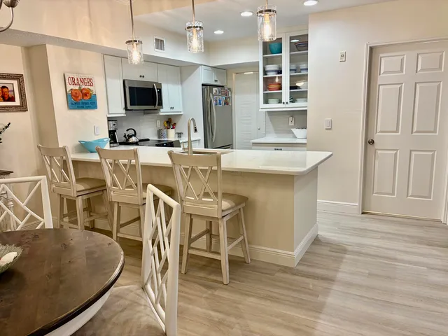 a kitchen with stainless steel appliances granite countertop a stove top oven a sink a dining table and chairs with wooden floor