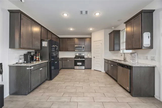 a large kitchen with stainless steel appliances lots of counter space sink and cabinets