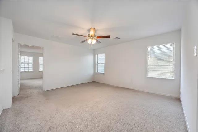 an empty room with windows and fan