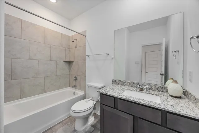 a bathroom with a granite countertop sink toilet mirror and bathtub