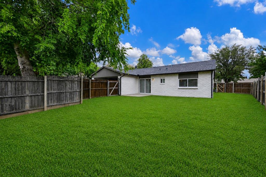 7318 Emory Oak Lane Dallas, TX 75249 - Photo 27 of 28 Spacious backyard featuring a manicured lawn, full privacy fencing, and mature trees