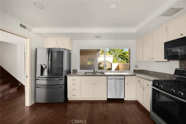 a kitchen with granite countertop a refrigerator stove and wooden floor