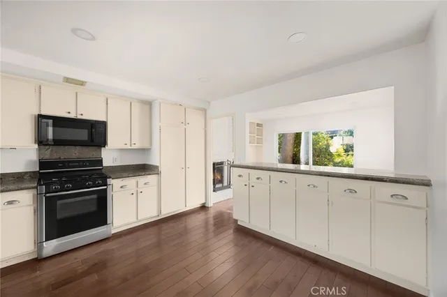 a kitchen with granite countertop white cabinets and stainless steel appliances