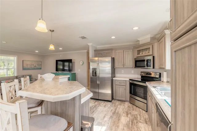 a kitchen with stainless steel appliances granite countertop a stove top oven a refrigerator a sink a dining table and chairs with wooden floor