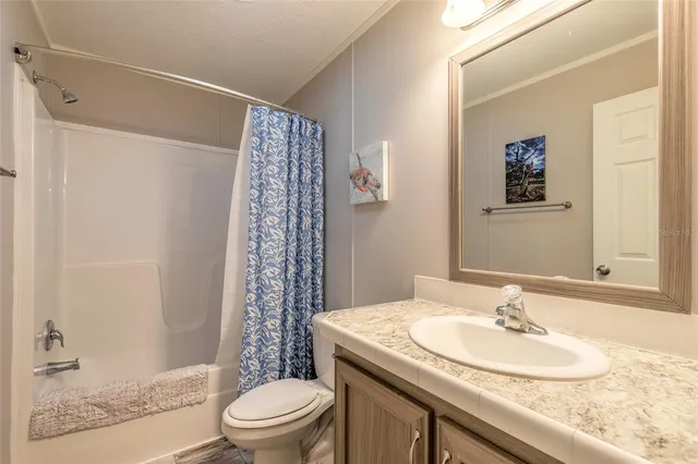 a bathroom with a granite countertop sink a toilet and shower