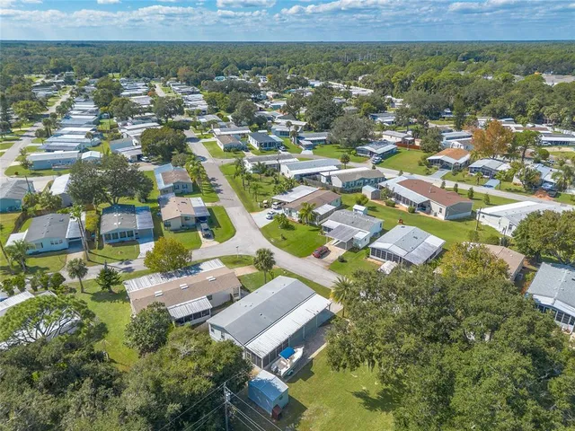 an aerial view of residential houses with outdoor space and trees