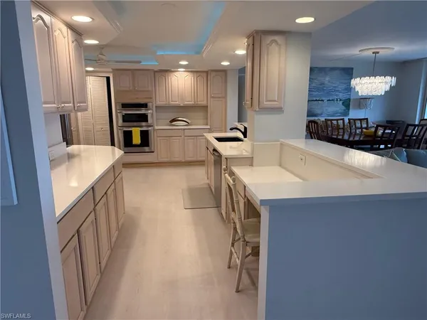 a large kitchen with a large counter top a sink stainless steel appliances and cabinets