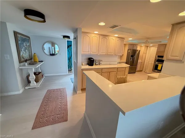 a very nice looking dining room with kitchen island a stove a refrigerator a dining table and chairs with wooden floor