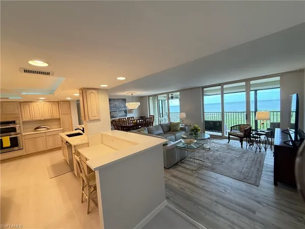 a large living room with stainless steel appliances granite countertop a couch and a large window