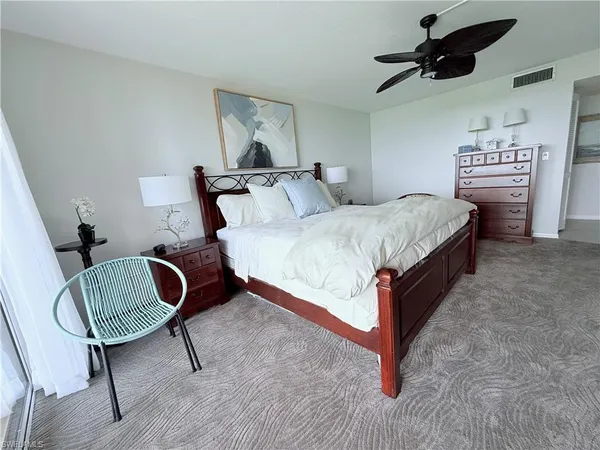 a bedroom with bed and a chair with wooden floor