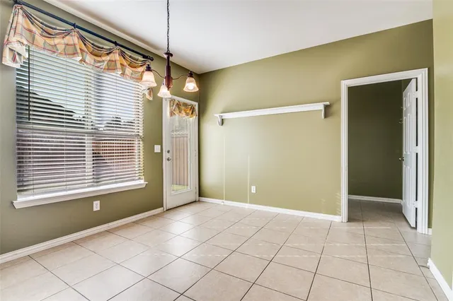 a view of an empty room with window and a kitchen